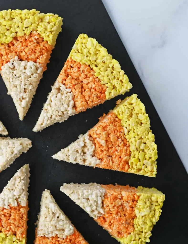 Triangle-shaped Rice Krispie treats layered in yellow, orange, and white to look like candy corn
