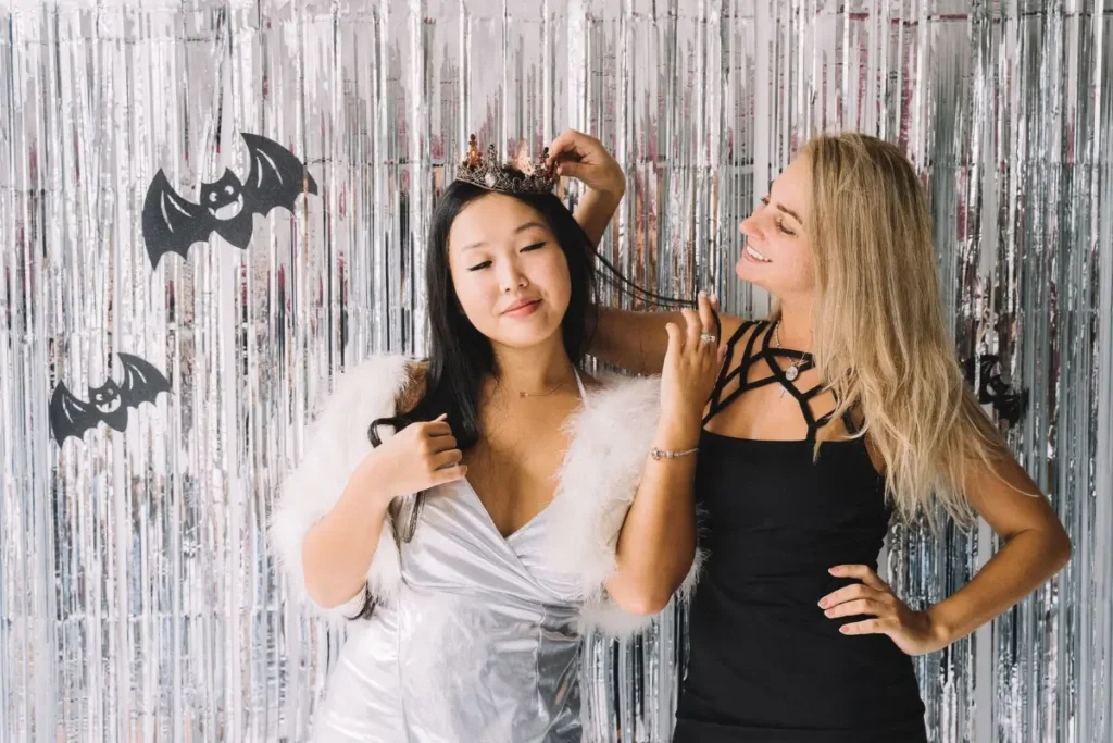 Two women in Halloween costumes enjoying a festive party with themed decorations