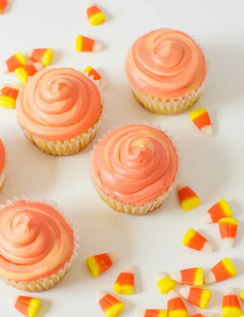 Vanilla cupcakes with yellow and orange swirled cake and candy corn decorations