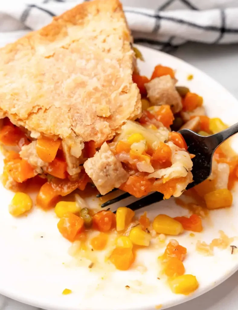 Vegan pot pie casserole with a golden crimped crust, sliced to show the vegetable filling