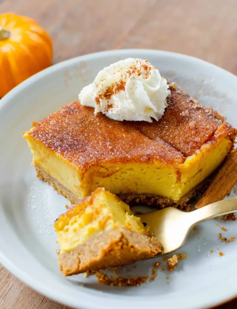 Vegan pumpkin snickerdoodle cheesecake bars topped with cinnamon sugar, cut into squares