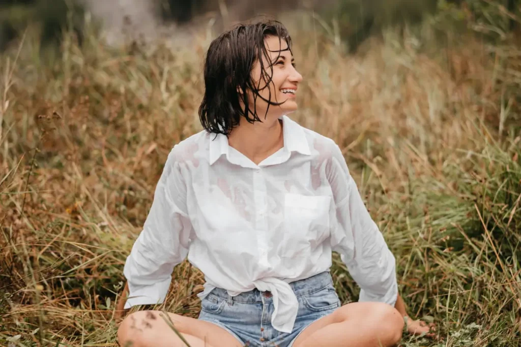 A woman sits cross-legged in a grassy field, enjoying a serene moment in nature