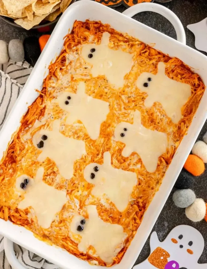 Baked buffalo chicken dip topped with melted mozzarella cheese cut into ghost shapes