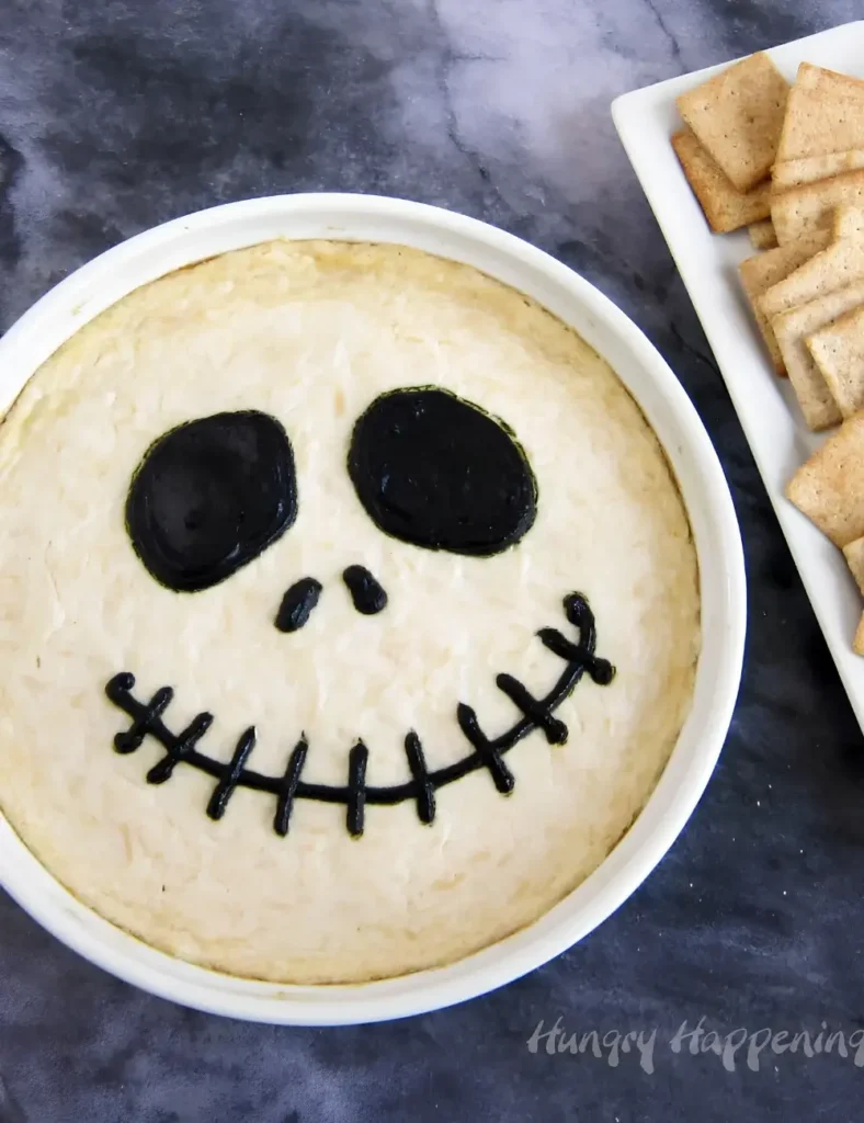 Baked chicken dip decorated with a black piped skeleton face design