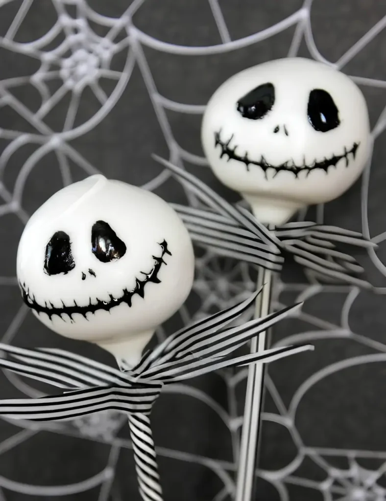 Black Halloween cake pops with hand-drawn faces and striped sticks, styled like a skeleton character