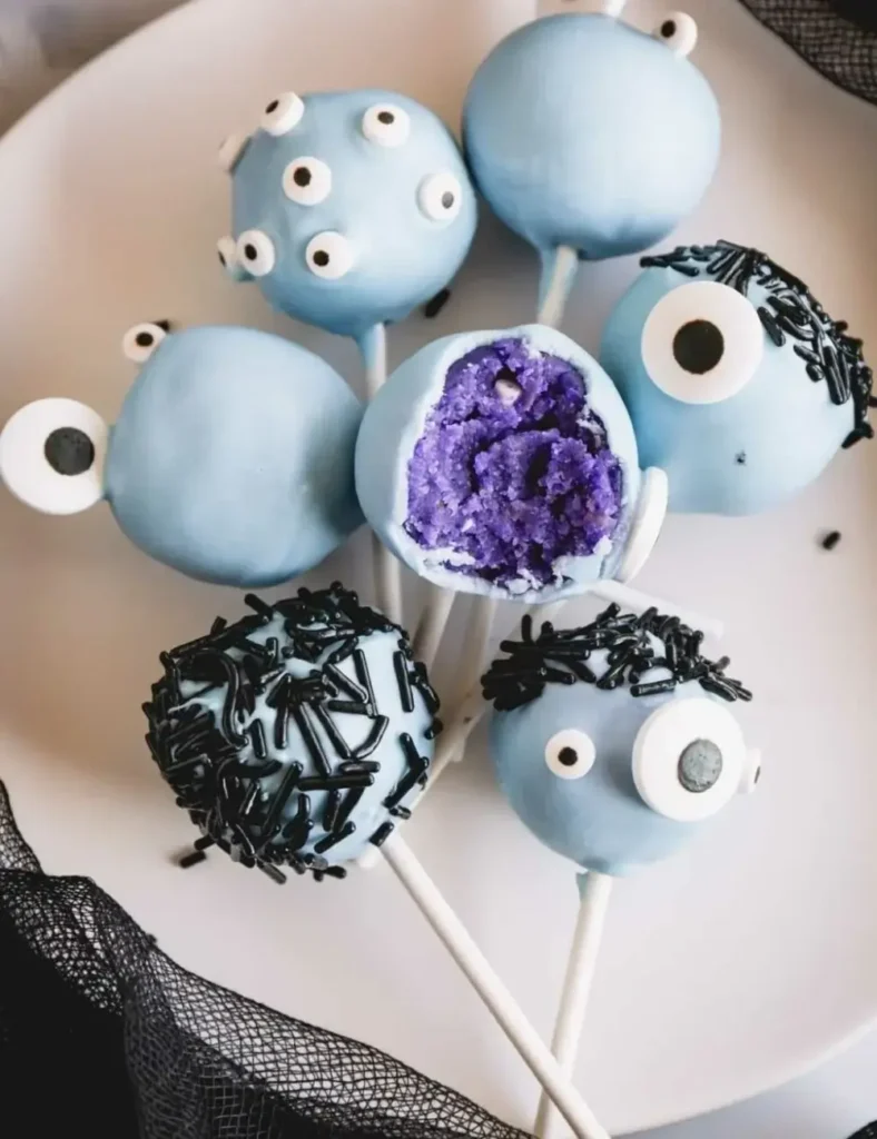 Blue monster Halloween cake pops covered in multiple candy eyes, with a bite taken out of one