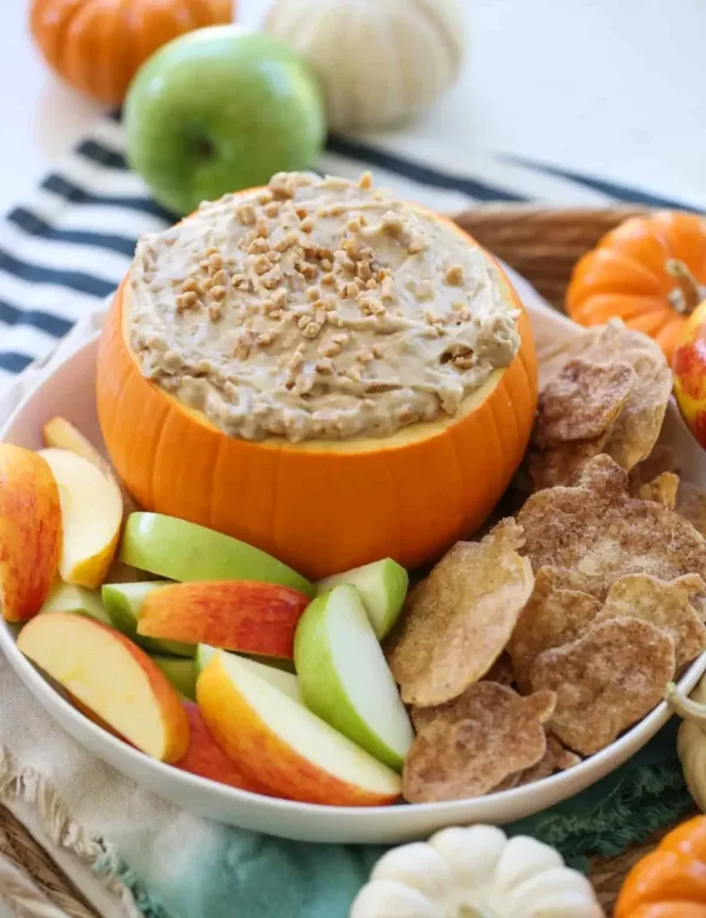 Caramel toffee fruit dip served in a hollowed-out pumpkin with apple slices and cinnamon tortilla chips
