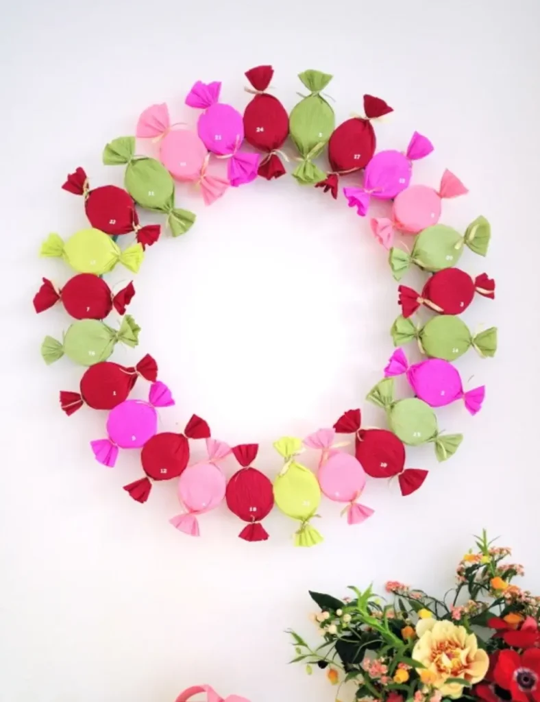 Colorful bonbon-wrapped advent calendar containers arranged in a wreath shape on a wall
