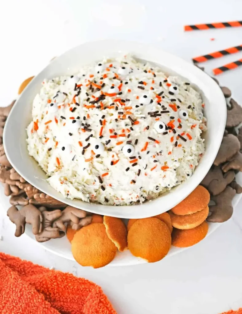 Fluffy Halloween cake mix dip topped with colorful sprinkles and candy eyes, served with cookies