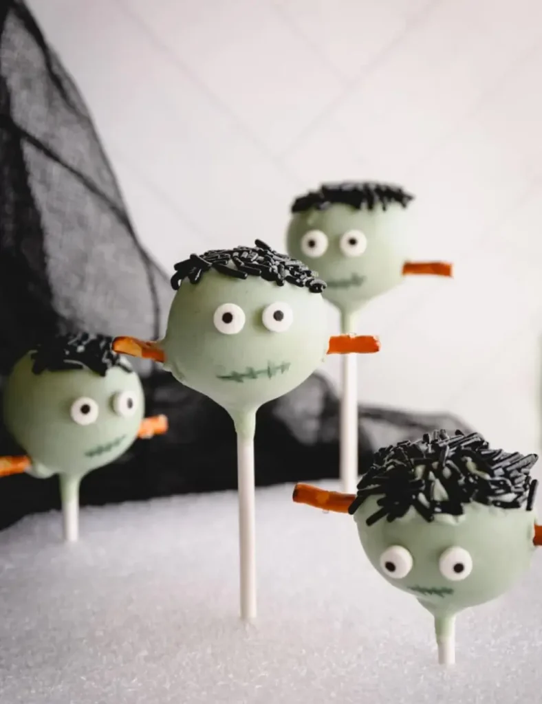 Green Frankenstein Halloween cake pops with pretzel-stick bolts and candy eyes, displayed upright