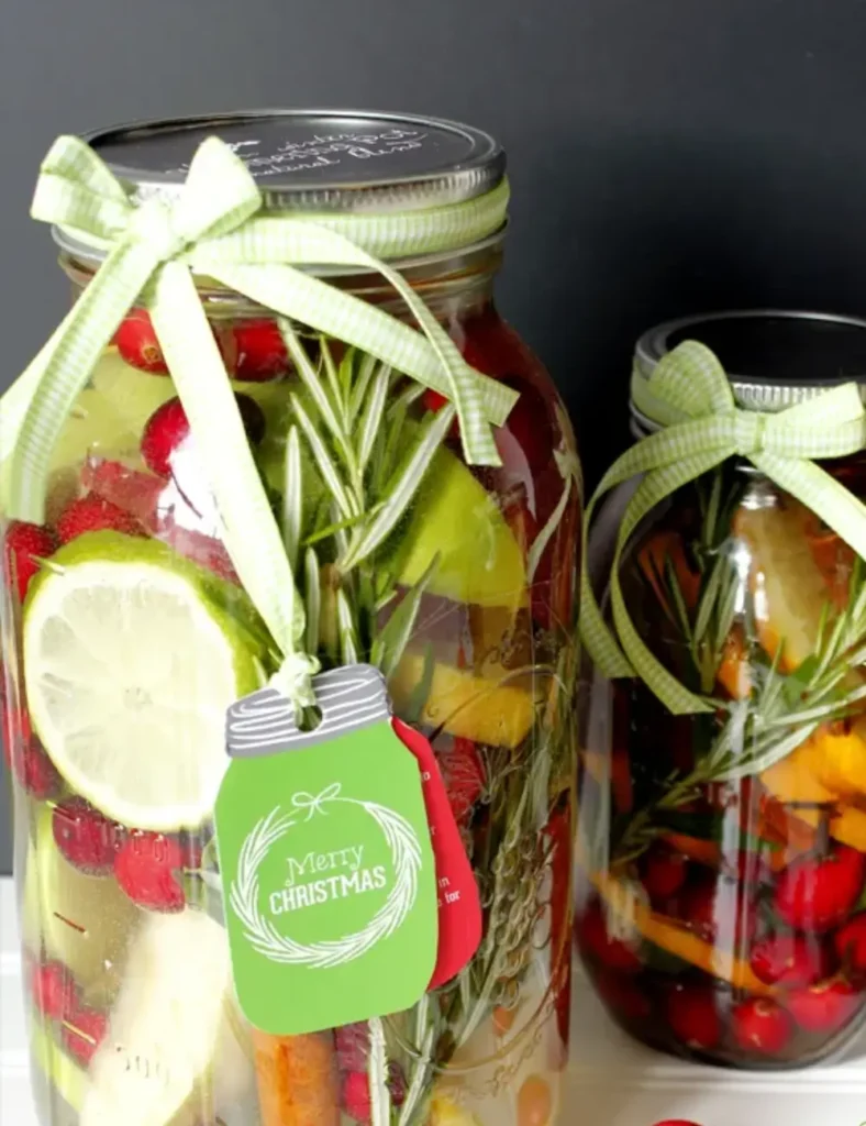 Mason jar filled with orange slices, cranberries, rosemary and cinnamon sticks, tied with a ribbon and a gift tag.