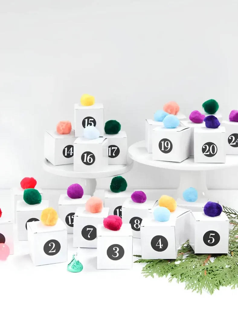 Mini numbered treat boxes topped with colorful pom-poms for a DIY advent calendar