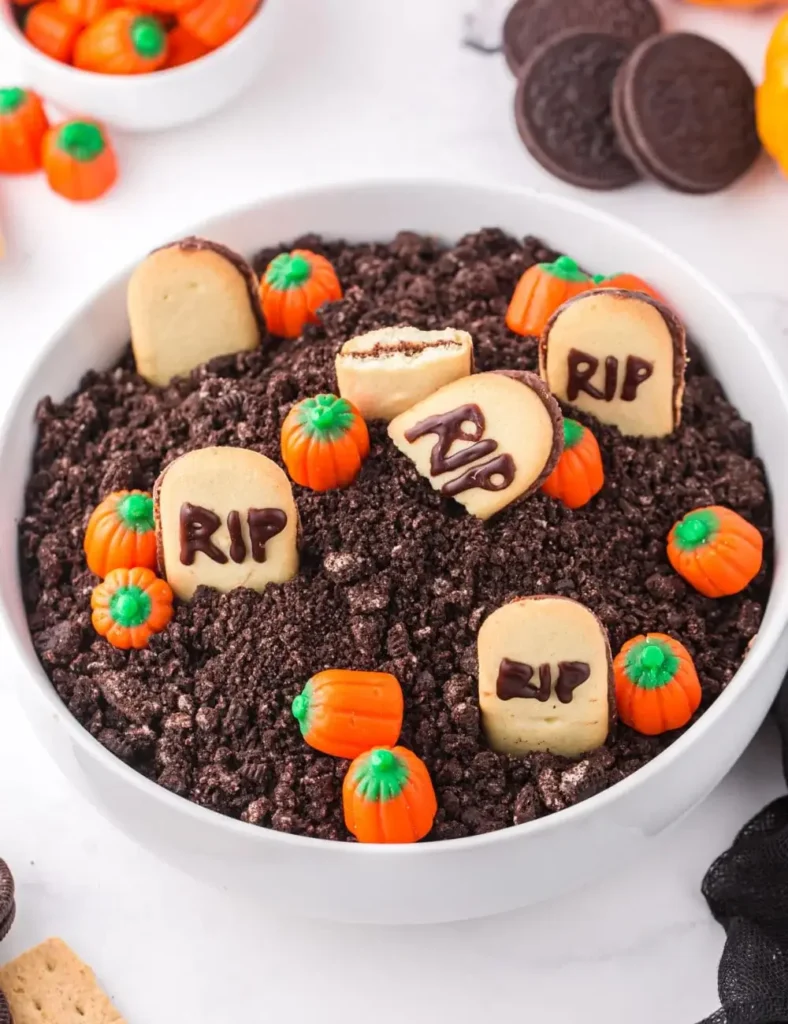 No-bake chocolate cheesecake dip topped with crushed cookie dirt and cookie tombstones for a graveyard scene