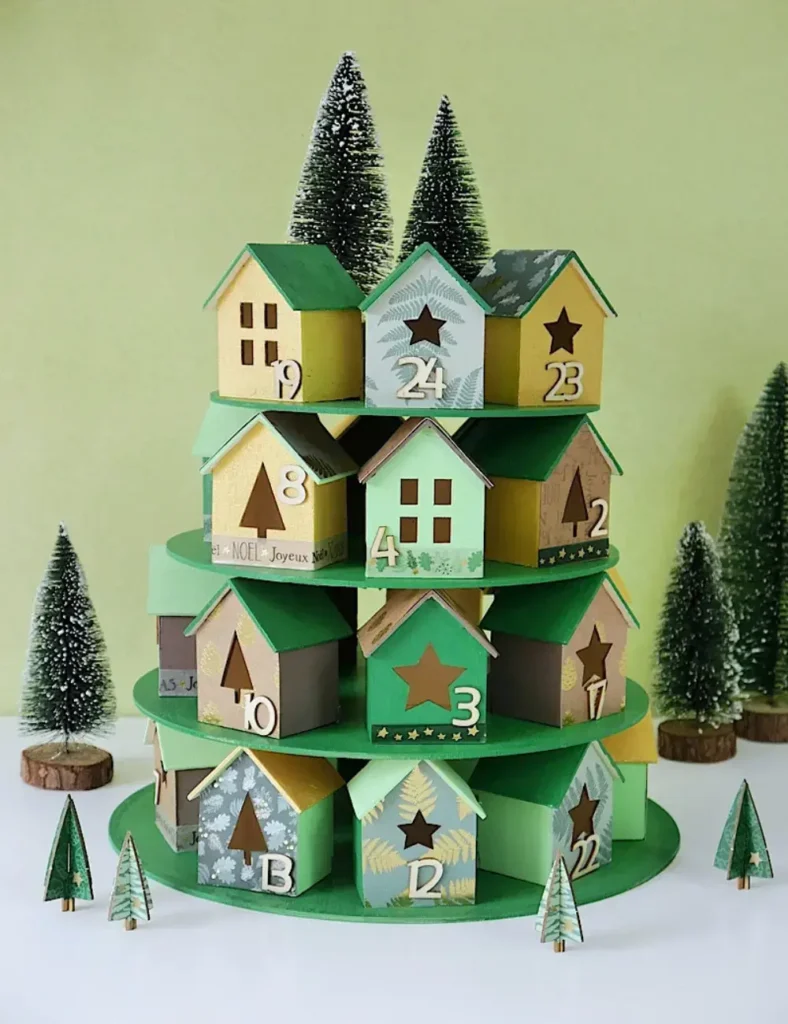 Painted wooden Christmas village houses with scrapbook paper roofs and advent numbers, displayed on tiered wooden plates