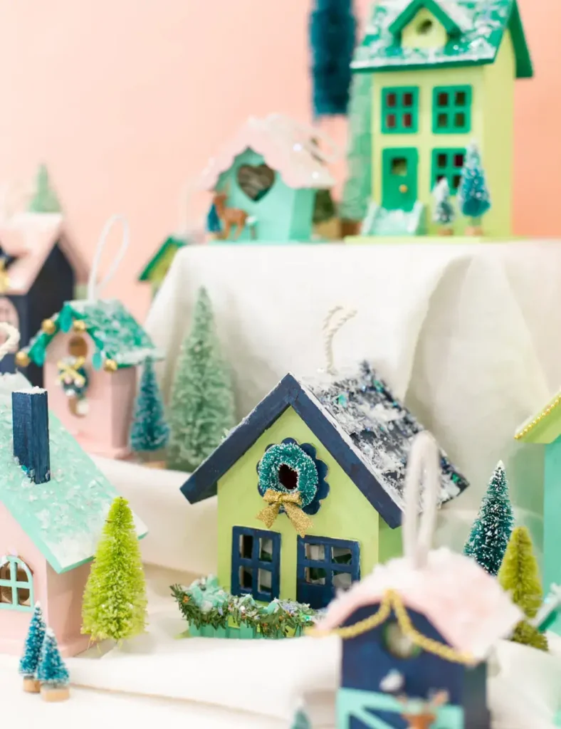 Painted wooden birdhouse Christmas village with number stickers and bottlebrush trees, each house holding a small wrapped gift