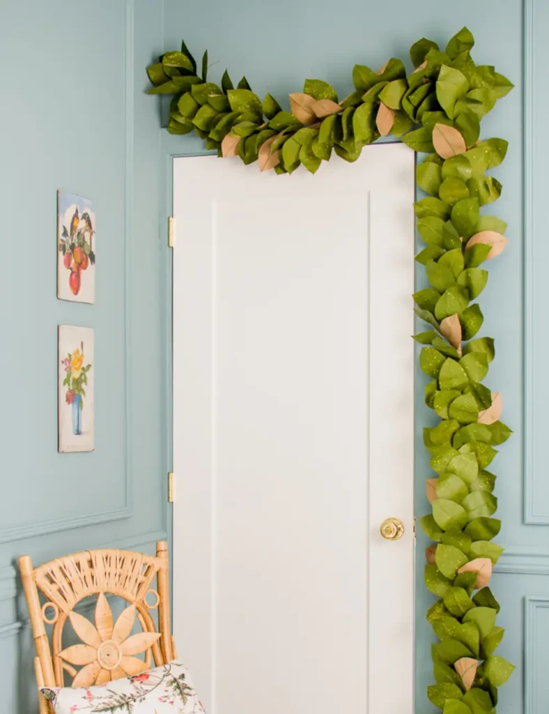 Paper magnolia leaf garland in two-tone green and brown draped over a door frame