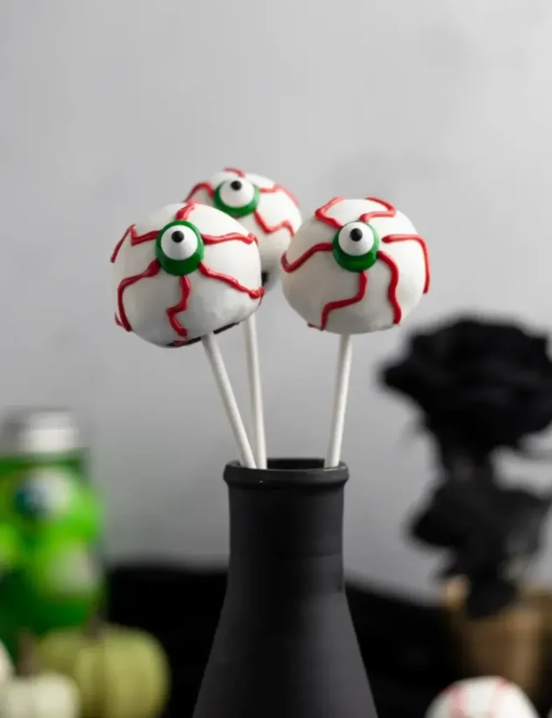 White chocolate eyeball Halloween cake pops with candy eyes and red veins, standing upright