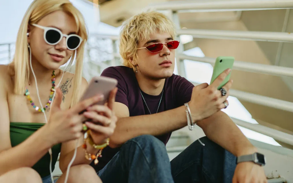 Young blonde couple using smartphones outdoors