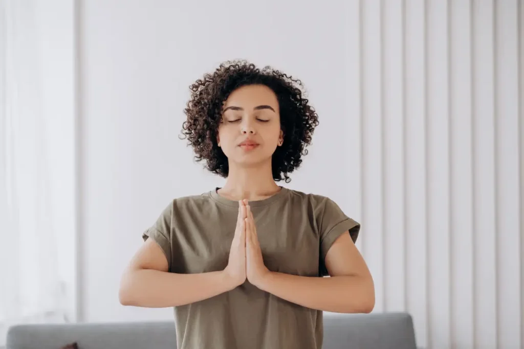 Young woman with curly hair meditates indoors, embracing tranquility and mindfulness